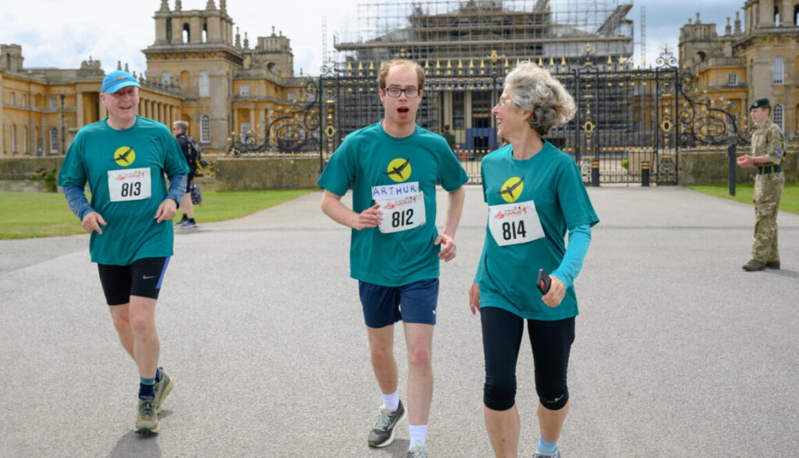 A picture of three people running towards the camera. In the background is Blenheim Palace, a large stately home.