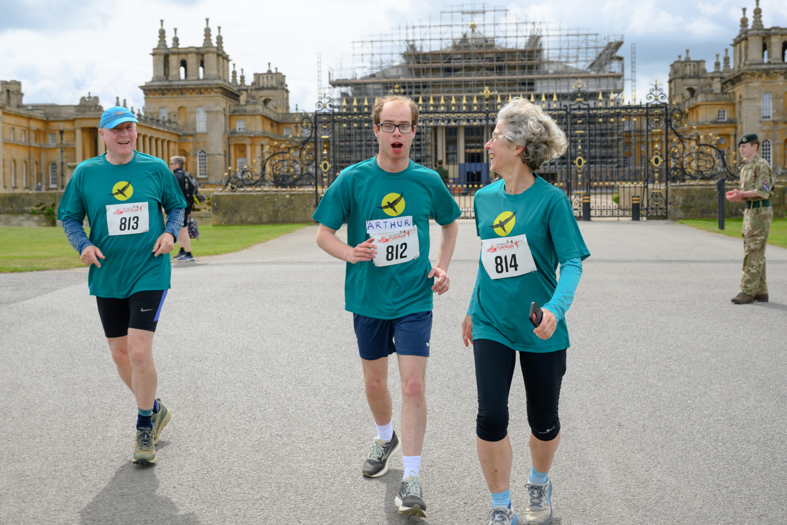 A picture of three people running towards the camera. In the background is Blenheim Palace, a large stately home.